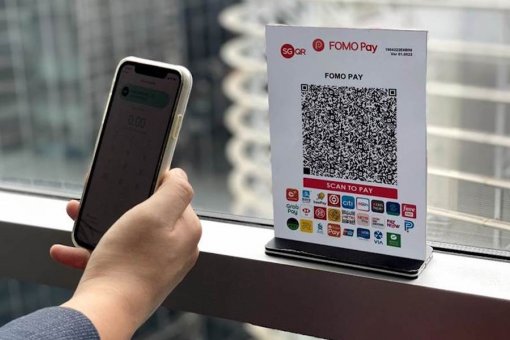 Рука, держащая телефон, сканирующая QR-код FOMO Pay